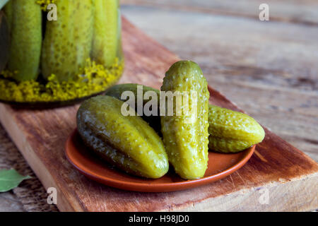 Eingelegtes Gemüse. Essiggurken (Gurken) auf Keramik-Platte über rustikalen hölzernen Hintergrund mit Textfreiraum. Stockfoto