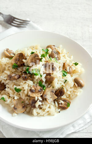 Pilz-Risotto mit Petersilie auf weißem Holz Hintergrund - gesunde vegetarische Ernährung Stockfoto