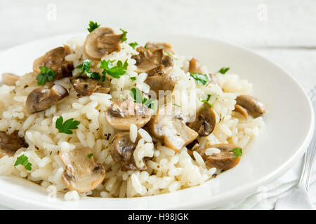 Pilz-Risotto mit Petersilie auf weißem Holz Hintergrund - gesunde vegetarische Ernährung Stockfoto