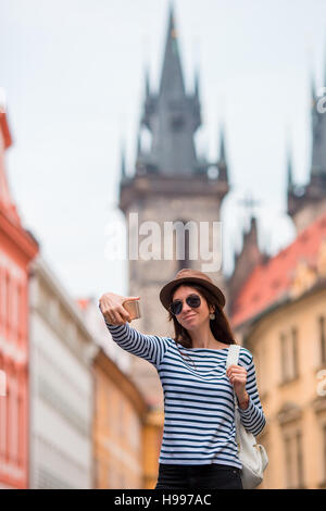 Glückliche junge Frau die Selfie Hintergrund berühmtes Schloss in europäischen Stadt. Kaukasische Touristen zu Fuß durch die verlassenen Straßen Europas. Warmen Sommer am frühen Morgen in Prag, Tschechische Republik Stockfoto