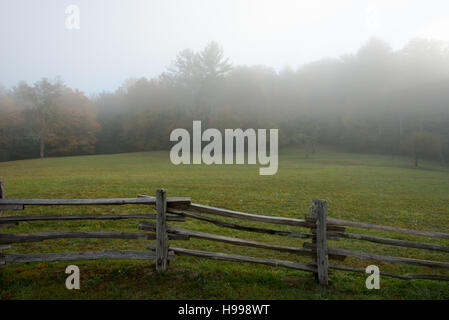 Ungleichmäßige Split Rail Zaun Linien Feld im Nebel Stockfoto