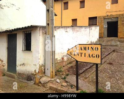 Ein gelbes Schild führt die Pilger durch ein ländliches Dorf entlang des Camino Frances in Nordspanien. Stockfoto