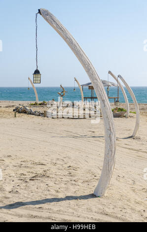 Reihe von Laternen hängen von Walknochen steckte in Sand am Strand in Angola mit Meer im Hintergrund. Stockfoto