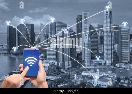 Hand mit Smartphone und Singapur Stadt mit Netzwerkverbindung. Smart-City-Netzwerk-Verbindung-Konzept. Stockfoto