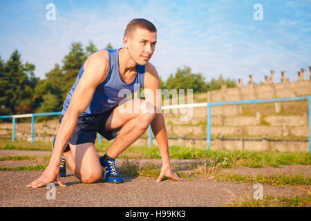 Mann in niedrigen Startposition im alten Stadion. Athlet in Ausgangsposition. Laufen, Joggen, Cardio, Sport, aktiven Lebensstil-Konzept. Stockfoto