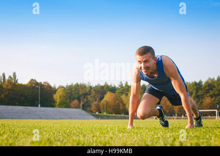 Mann in niedrigen Startposition im alten Stadion. Athlet in Ausgangsposition. Laufen, Joggen, Cardio, Sport, aktiven Lebensstil-Konzept. Stockfoto