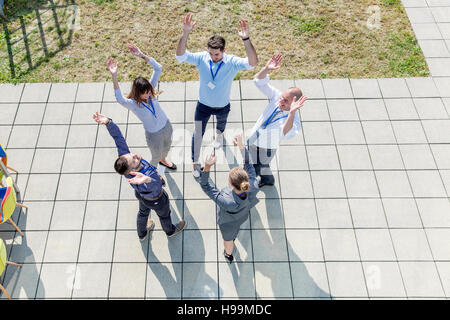 Gruppe von Geschäftsleuten, die Hände in einem Kreis zusammen erhebend Stockfoto