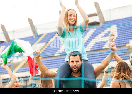 Fußball-Fans hinter Zaun feiert mit italienischer Flagge Stockfoto
