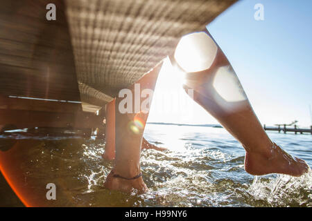 Junge Frauen sitzen auf Pier, die Füße im Wasser Baden Stockfoto