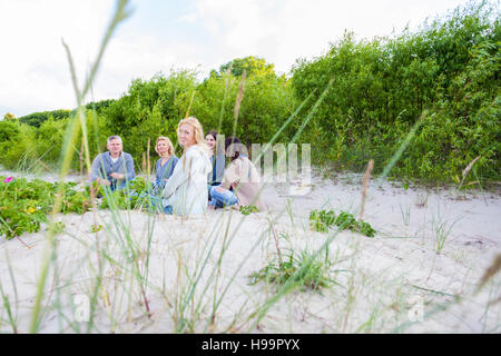 Gruppe von Freunden sitzen am Sandstrand Stockfoto