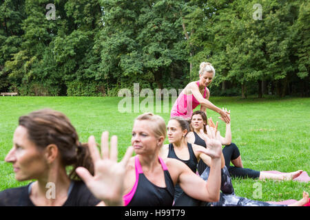 Junge Frau lehrt Yoga-Kurs im park Stockfoto