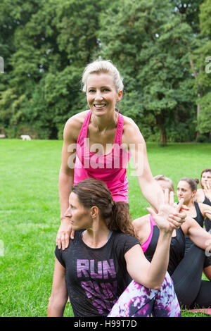 Junge Frau lehrt Yoga-Kurs im park Stockfoto