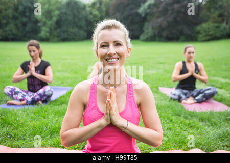 Junge Frauen praktizieren Yoga im Park Hände gefaltet Stockfoto