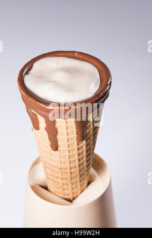 Kaffee im Waffelhörnchen in Schokolade getaucht, mit Zeichnungen in Cappuccino / Latte Milchschaum, Latte Art, isoliert Stockfoto