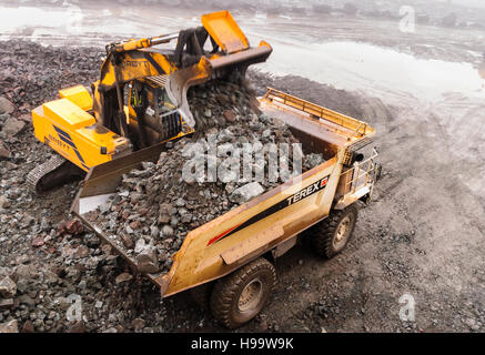 Ein Broyt verfolgt Loader lädt ein Rock-Muldenkipper Terex in einem Steinbruch bei starkem Regen. Stockfoto