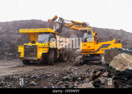 Ein Broyt verfolgt Loader lädt ein Kubota-465-Rock-Muldenkipper in einem Steinbruch bei starkem Regen. Stockfoto