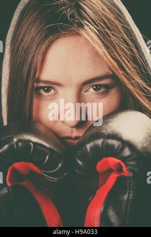 Bekämpfung von Boxen und Verteidigung. Sportlichkeit und starken Körper. Junge Frau tragen Sportswear und Boxhandschuhe Abdeckung Gesicht schauen Gegner. Stockfoto