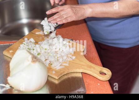 Nahaufnahme der senior Frau Hand schneiden Zwiebel. Flachen Dof, selektiven Fokus auf der Hand. Stockfoto