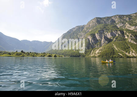 Zwei Personen in einem gelben Kajak auf dem Bohinjer See, Slowenien, mit Klippen der Berge der Julischen Alpen im Hintergrund Stockfoto