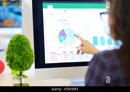 Über die Schulter-Blick auf eine Geschäftsfrau arbeiten am Computer und auf Grafik zeigen Stockfoto