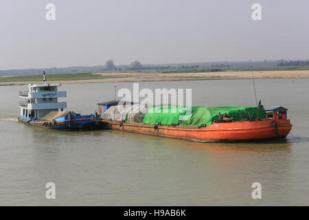 Ein Fluss Frachtboot drücken ein Lastkahn stromaufwärts auf dem Irrawaddy in Myanmar (Burma). Stockfoto