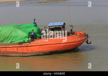 Crew auf ein Binnenschiff Fracht gehen flussaufwärts, Welle an Touristen auf einem Kreuzfahrt-Schiff auf dem Irrawaddy in Myanmar (Burma). Stockfoto