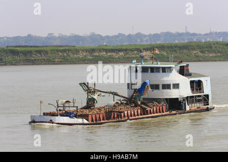 Ein Fluss Schaufler Boot Heads flussaufwärts auf dem Irrawaddy in Myanmar (Burma) mit einer Belastung von gebrochenen Felsen (Regulierungsdeich). Stockfoto