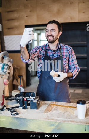 Zimmermann nimmt ein Selbstporträt mit Gehrung sah an seinem Arbeitsplatz Stockfoto
