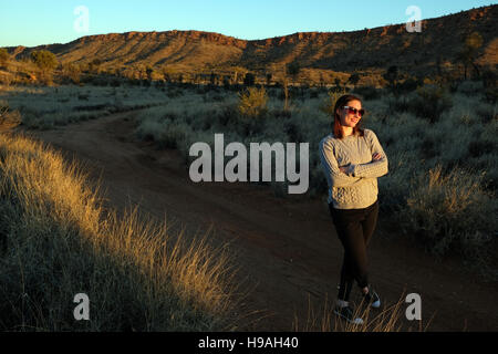 Eine Frau beobachtet den Sonnenuntergang in den MacDonnell Ranges, Alice Springs, Northern Territory, Zentral-Australien Stockfoto