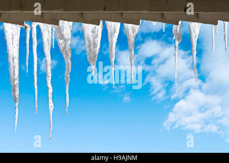 Eiszapfen hängen von dem Dach gegen bewölktem Himmel Stockfoto