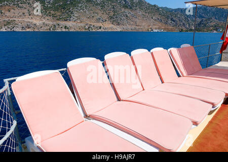 Rosa Sonnenliegen auf einem Boot im Meer, Türkei