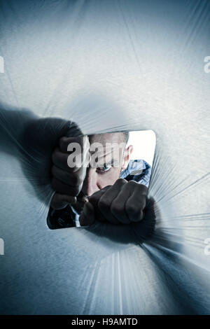 Ein Mann durch ein Loch in Polyethylen Blatt zerrissen Spionage. Stockfoto