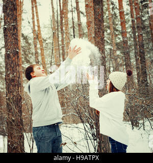 Junge liebende Paare, die Spaß im Winterwald, Winter Urlaub Konzept, getönt Stockfoto