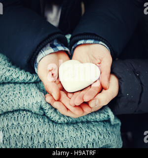 Mann und Frau Hände halten Lebkuchenherz in weißem Zuckerguß, close-up. Valentine Day Feiertag. Getönten Stockfoto