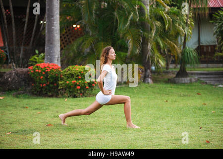 Junge Fitness-Mädchen machen Übungen auf dem Rasen im Park. Gesunder Lifestyle und Sport-Konzept Stockfoto