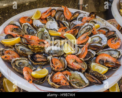 Fischplatte von Garnelen und rohe Austern, abgerundet mit Zitronenscheiben Stockfoto