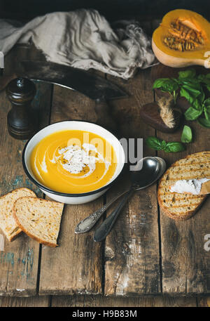 Kürbis Cremesuppe mit frischem Basilikum, Gewürze und gegrilltem Brot Stockfoto