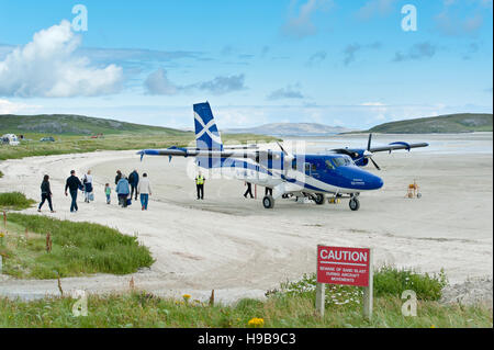 Flughafen und Flugzeug Twin Otter von schottischen Fluglinie Loganair, Passagiere beim boarding, Flugplatz am Sandstrand, Barra Airport Stockfoto