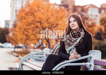 Junge Frau sitzt auf der Bank Stockfoto