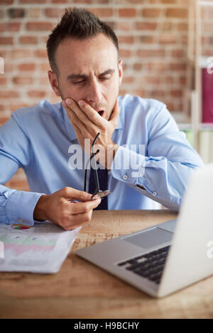 Mann über den Laptop Gähnen Stockfoto