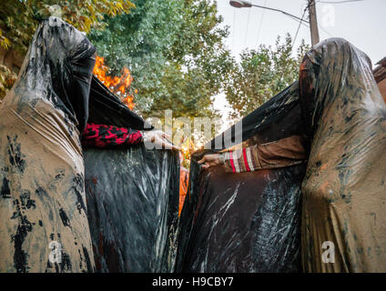 Iranische Schiiten muslimische Frauen versammeln sich um ein Lagerfeuer nach reiben Schlamm auf ihren Tschador während des Kharrah Mali Rituals anlässlich den Aschura-Tag, Lorestan Stockfoto