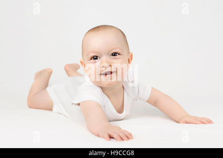 Baby Junge auf dem Bauch liegend lächelnd auf den weißen Hintergrund Stockfoto