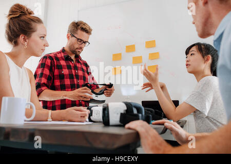 Gruppe von Jugendlichen im Konferenzraum mit augmented-Reality-Geräten auf Tisch treffen. Verschiedene Business-Team im Tagungsraum mit virtual-Reality-g Stockfoto