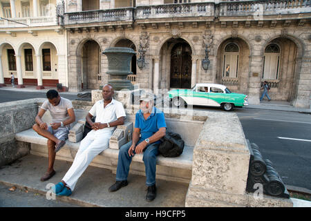 drei kubanische Männer sitzen auf den geschnitzten Stein kolonialen sitzen entlang des Paseo de Prado in Centro Havanna Kuba Stockfoto