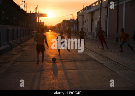 Silhouetten von kubanischen Jugendliche Fußball auf der Straße spielen, wenn die Sonne untergeht dahinter in Cienfuegos Kuba Stockfoto