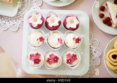 In der Nähe dekoriert, Cupcakes auf Tablett mit rosa Blüten Stockfoto