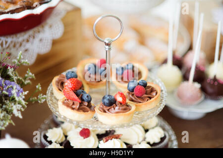 Tisch mit frischem Obsttorten, Cupcakes und bunten cakepops Stockfoto