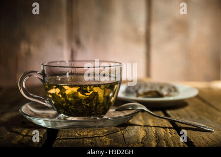Glastasse grünen Tee, Teelöffel und Honig Kuchen auf Holztisch Stockfoto