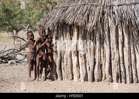Kinder von einheimischen Himba-Stamm in traditioneller Kleidung spielen mit einander in der Nähe ihrer Hütte am Kunene Region von Namibia Stockfoto