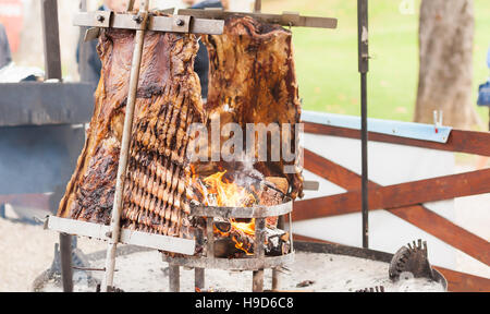 Asado, traditionellen Barbecue-Gericht in Argentinien, gebratenes Fleisch Rindfleisch gekocht auf einem vertikalen Grill um Feuer gelegt Stockfoto